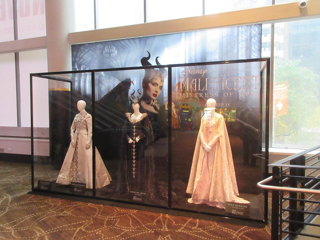 Utsmyckade filmkostymer från Disneys Maleficent utställda i en monter.